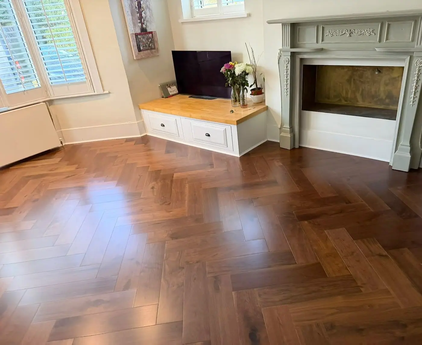 Walnut herringbone floor in a living room with a period fireplace and window shutters