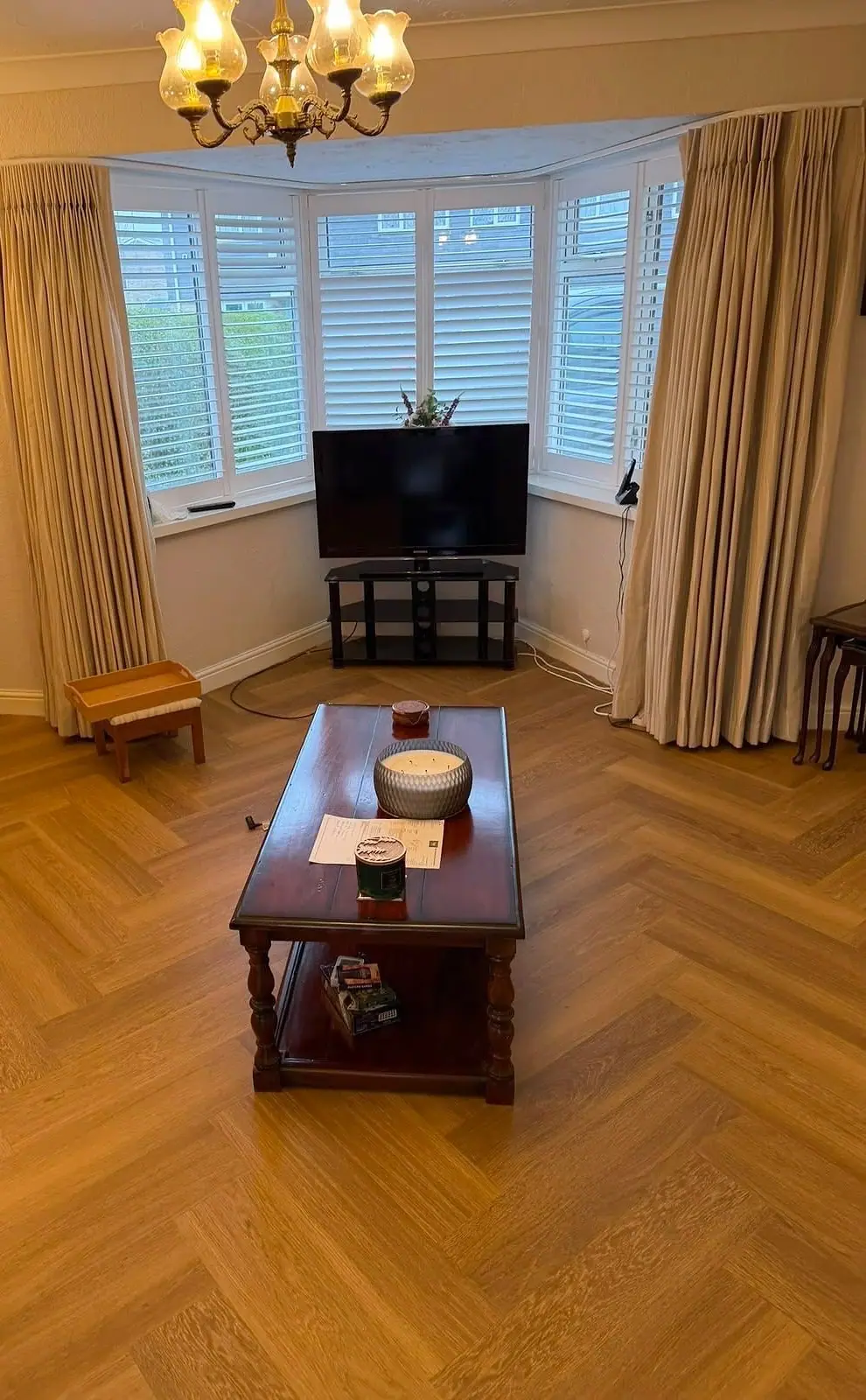 Honey-toned herringbone floor in a living room with a bay window