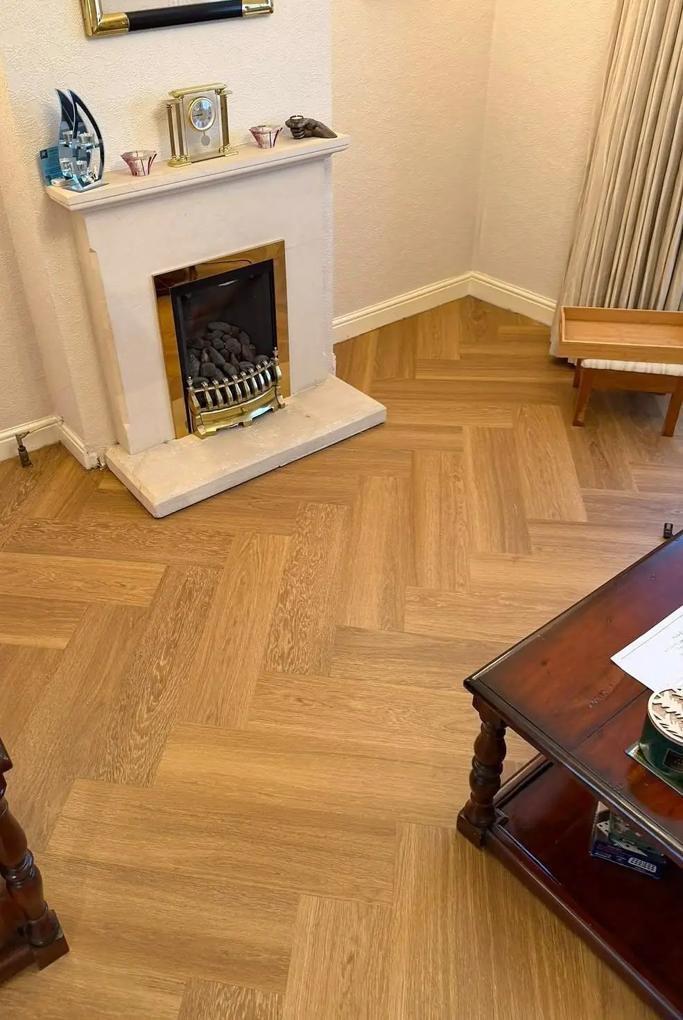 Honey-toned herringbone floor in a living room with a fireplace