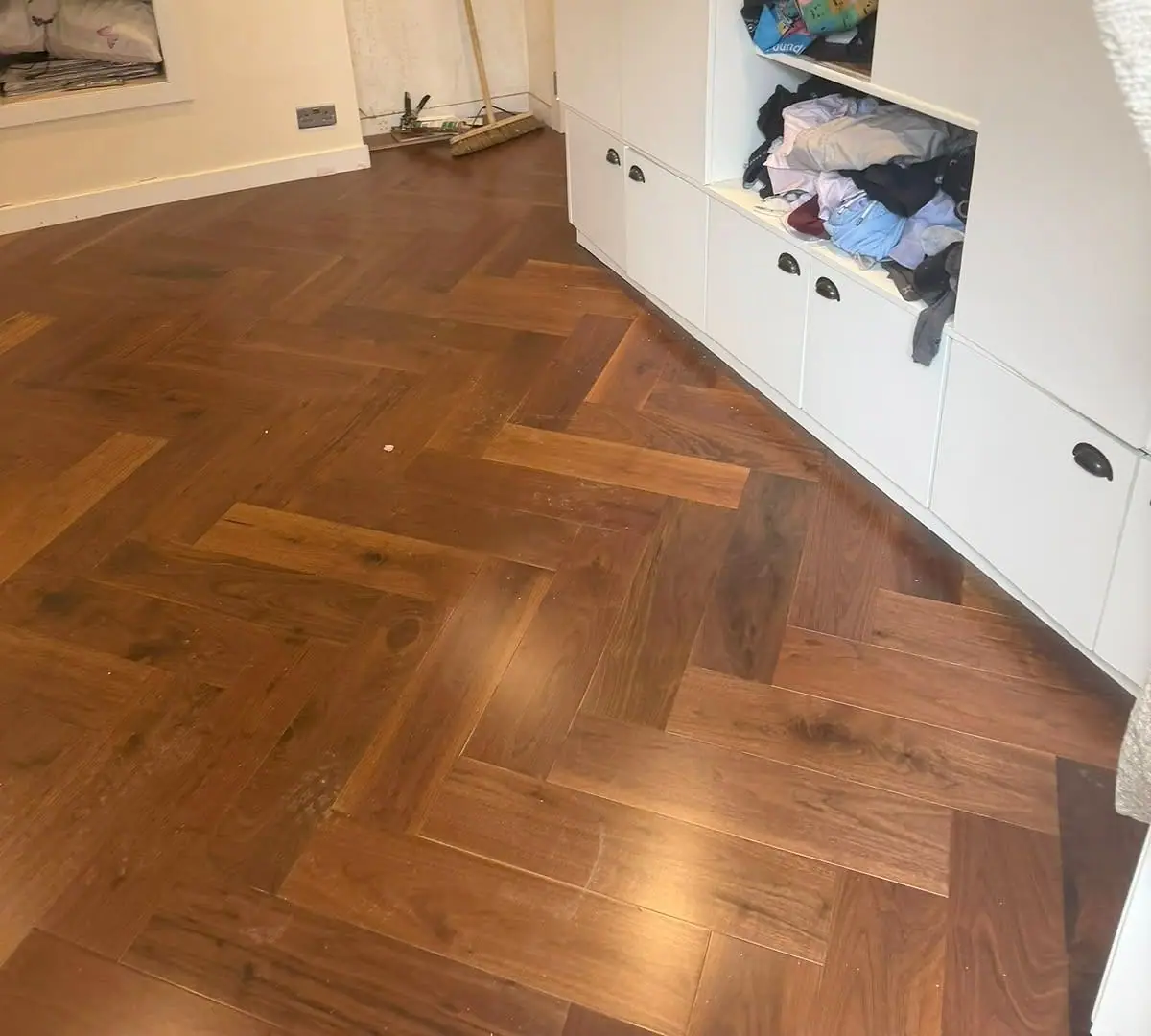 Walnut herringbone floor fitted up to built-in cupboards