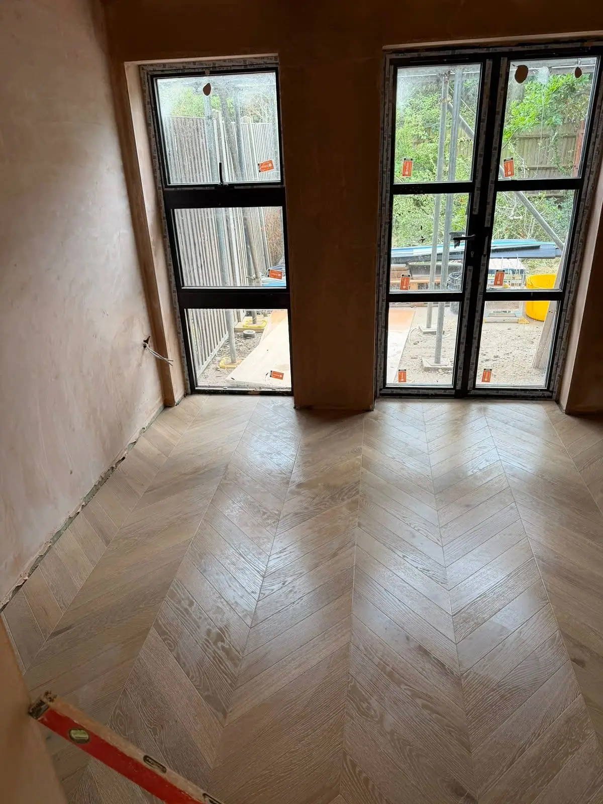 Light oak chevron floor in a freshly plastered room with garden doors