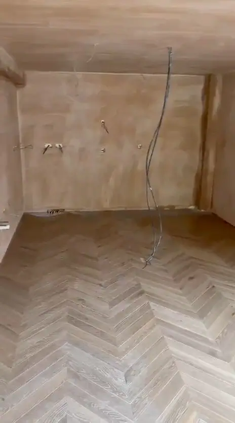 A newly laid chevron floor in a freshly plastered room